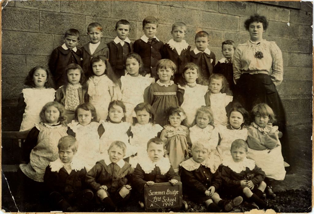 Black and white group photograph showing 27 pupils in the Infants class with their teacher